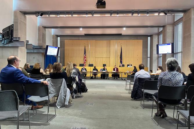 Department of Health officials seated at a public meeting.
