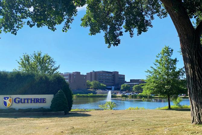 A health system campus framed by trees with a sign that says “Guthrie.” A health system campus framed by trees with a sign that says “Guthrie.”