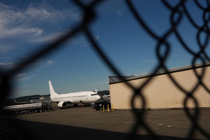 An airplane and a building seen through a chain link fence. An airplane and a building seen through a chain link fence.